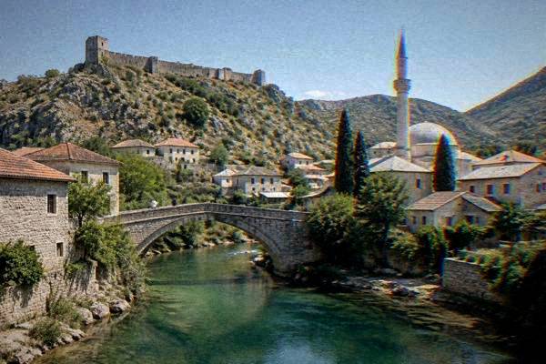 An old stone-walled town on a rocky hill beside a river, with a a slender stone tower beside a mosque and tiled roofs, midday light, Stolac