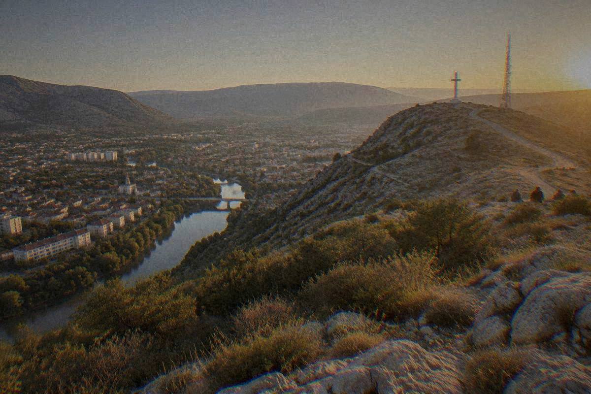 Hum Hill above Mostar, a bare limestone hillside with scrub and loose rock, a view down over the city and the river valley, Brdo Hum