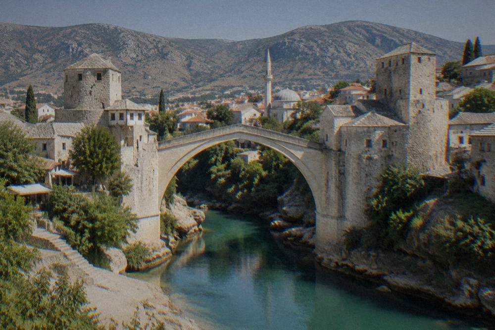 A view from the riverbank of the Old Bridge with the Old Town rooftops and minaret behind it