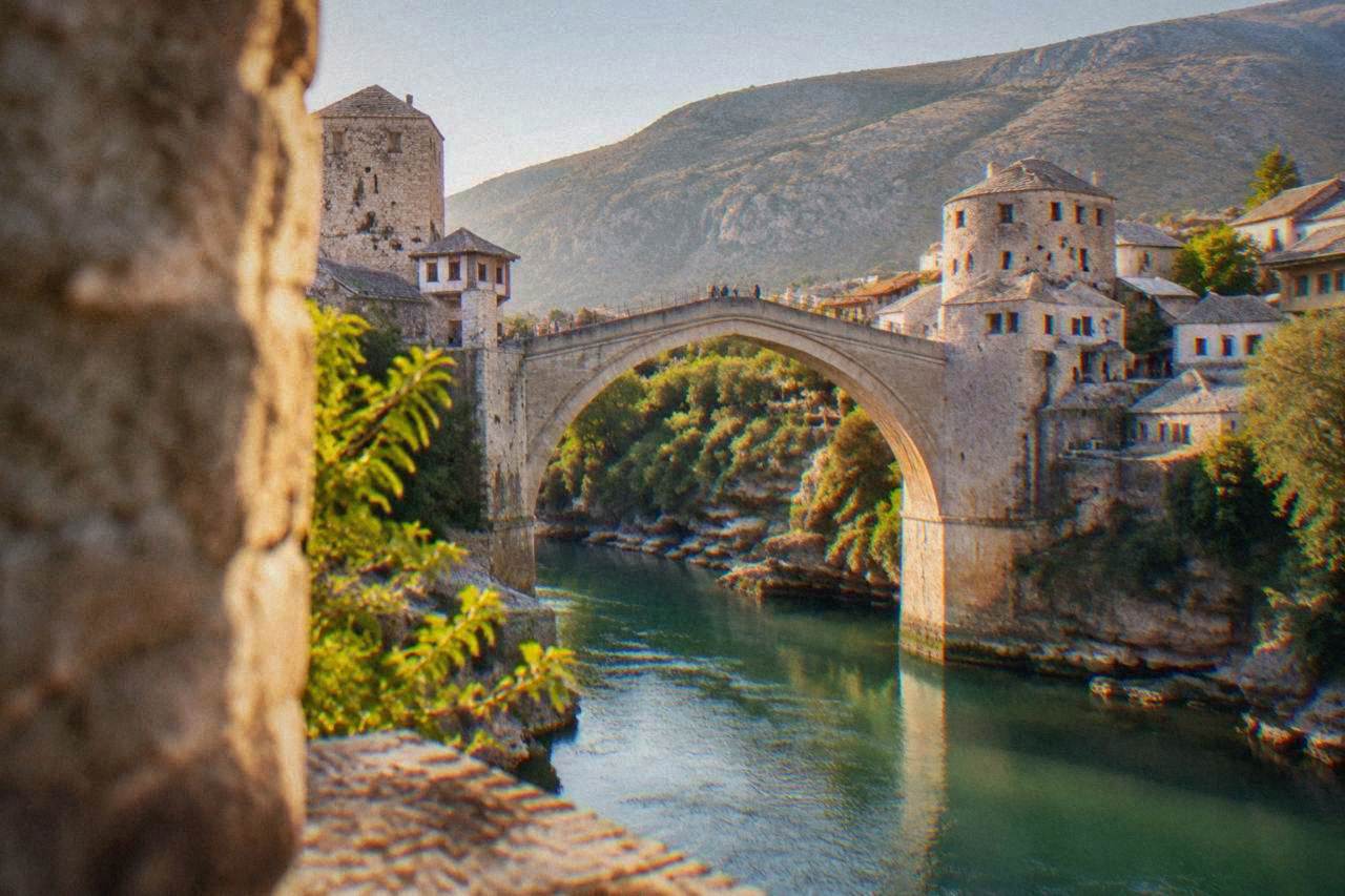 The Old Bridge in Mostar arching over the green Neretva river at midday