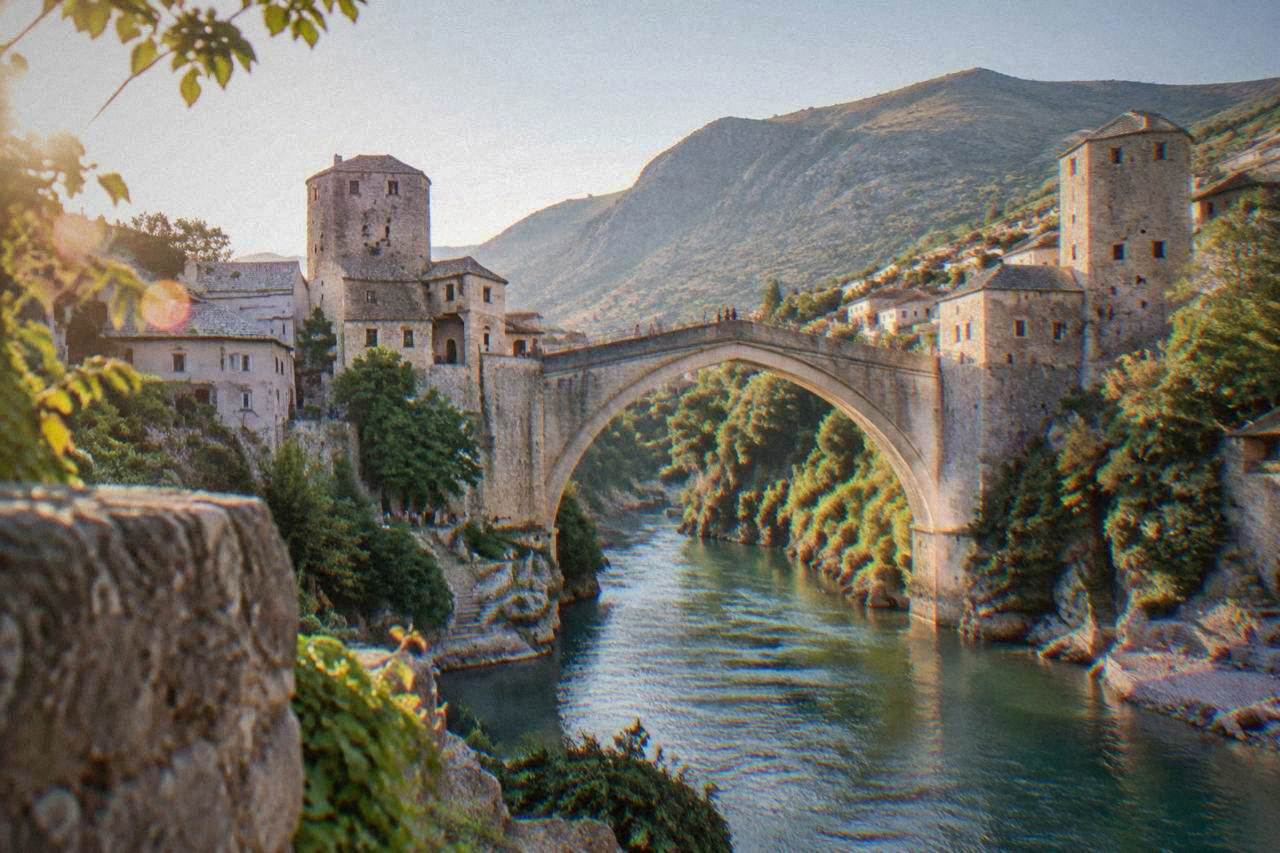 The stone arch of Stari Most rising over the green Neretva river in Mostar