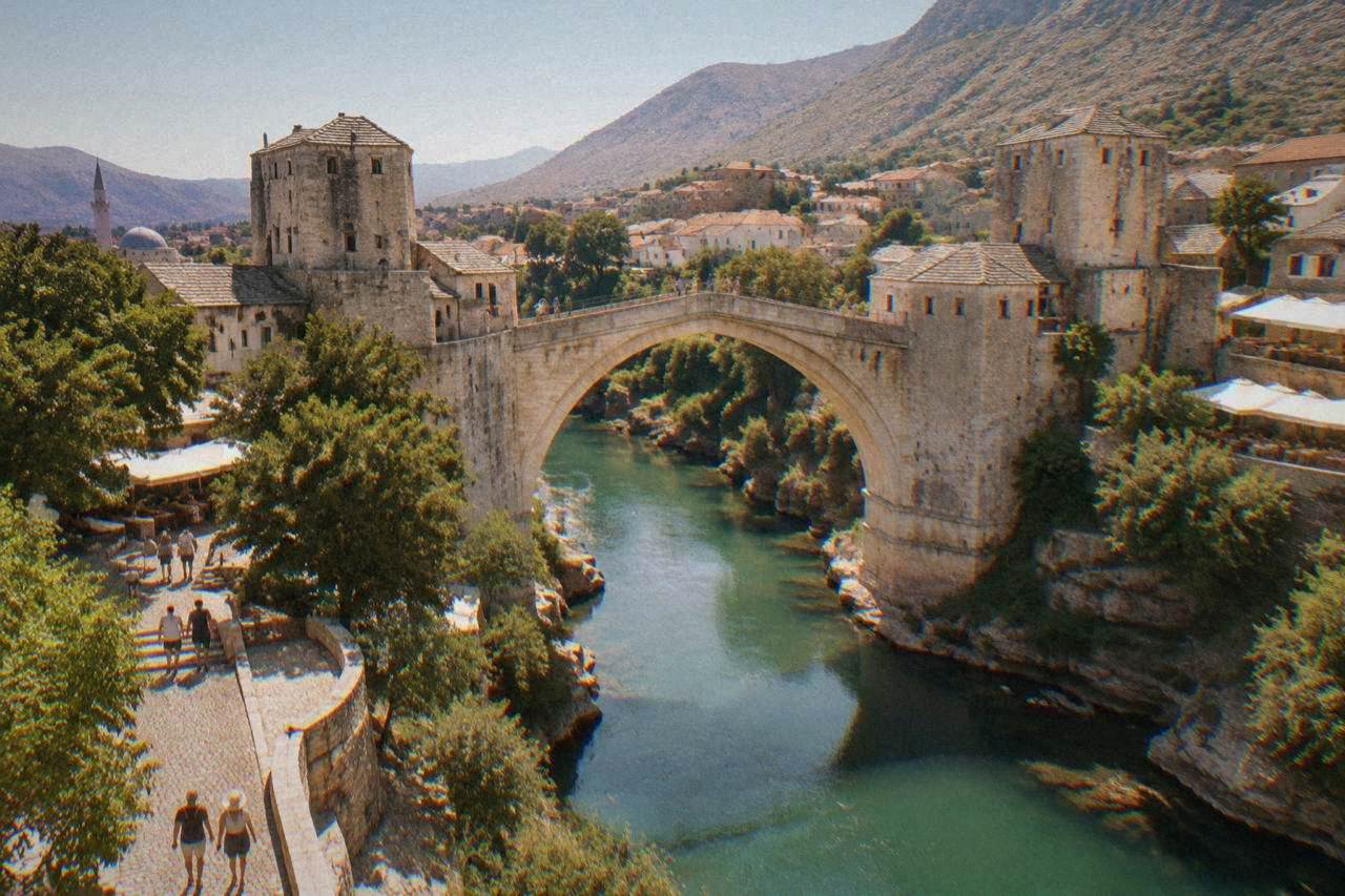Sunlit stone buildings of the Old Bridge area of Mostar under a clear summer sky