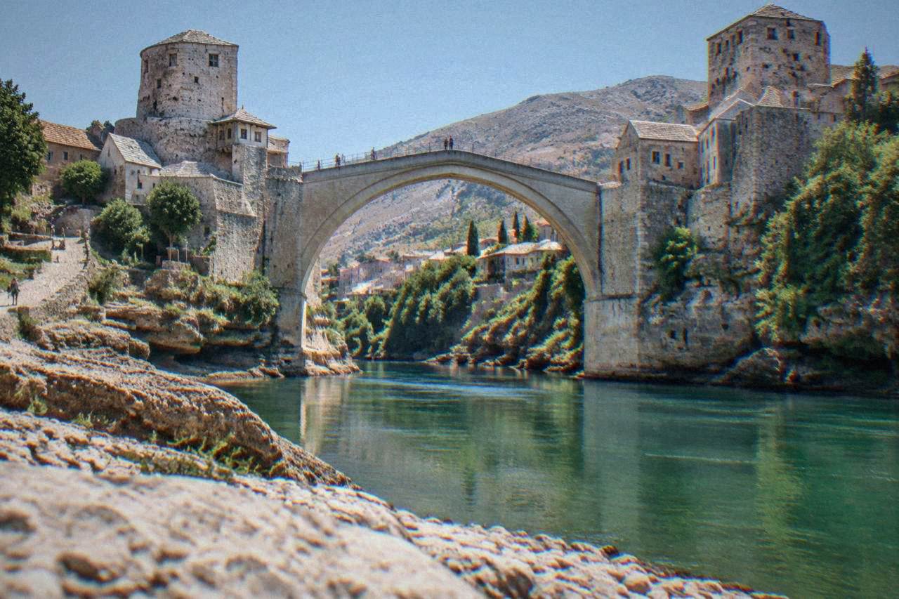 The stone arch of the Old Bridge in Mostar seen from the riverbank with the Neretva flowing below