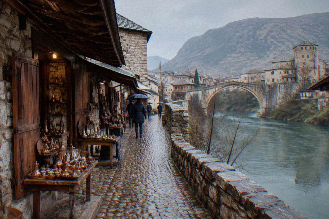 Quiet street of stone houses on the Neretva riverbank in Mostar with the hills behind