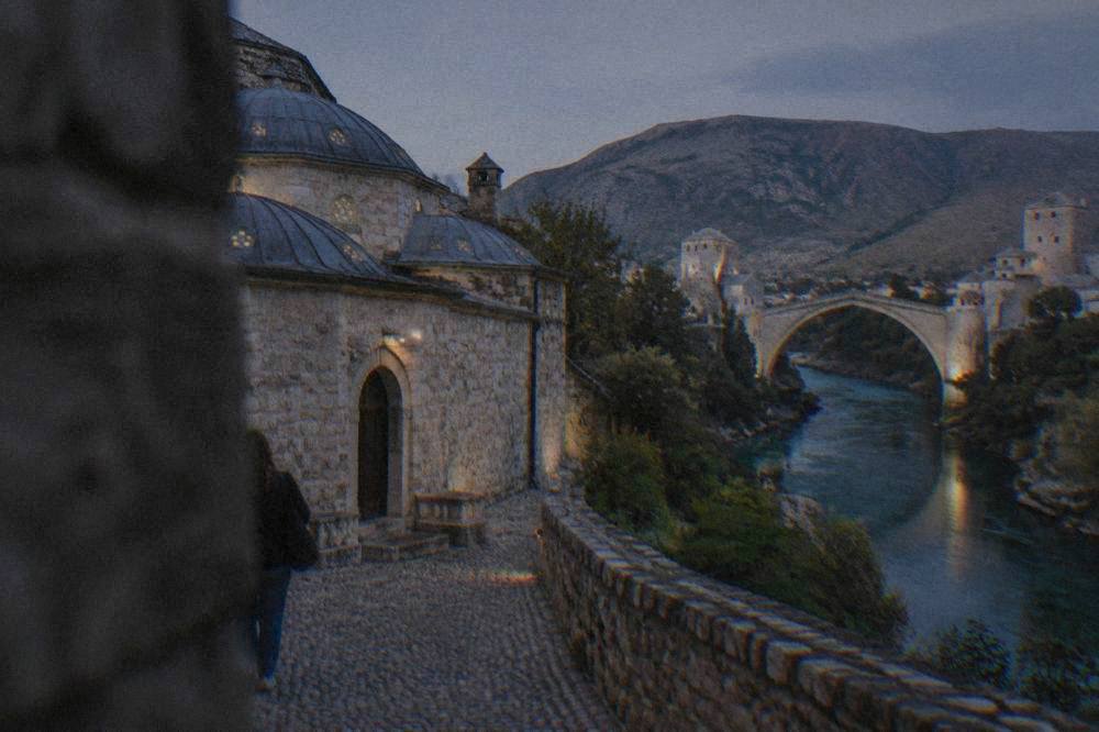 The turquoise Neretva river seen from the east bank path with Stari Most in the distance
