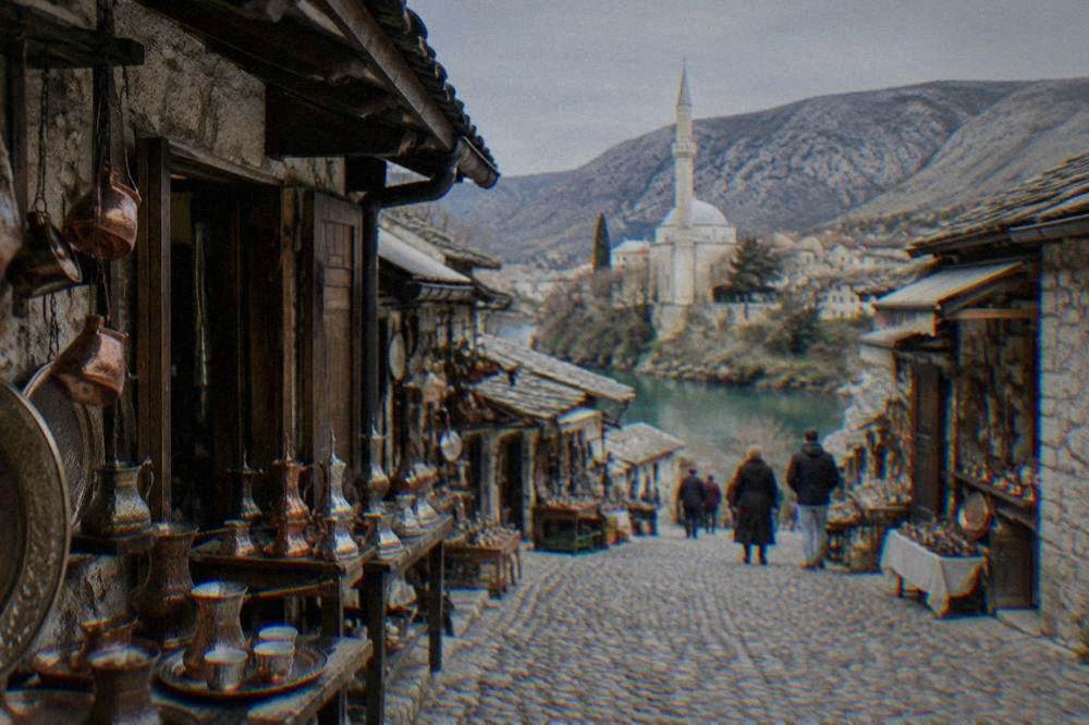 A mosque with a minaret standing directly above the green river in the Old Town