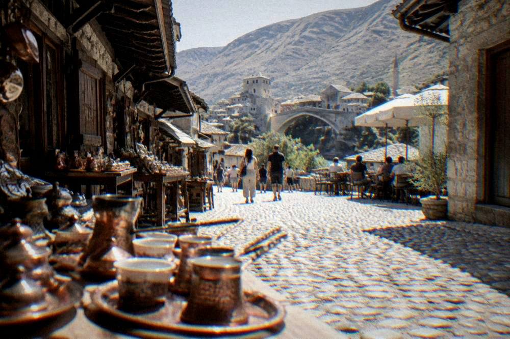 A stone-paved square in the Old Town with cafe tables and people strolling