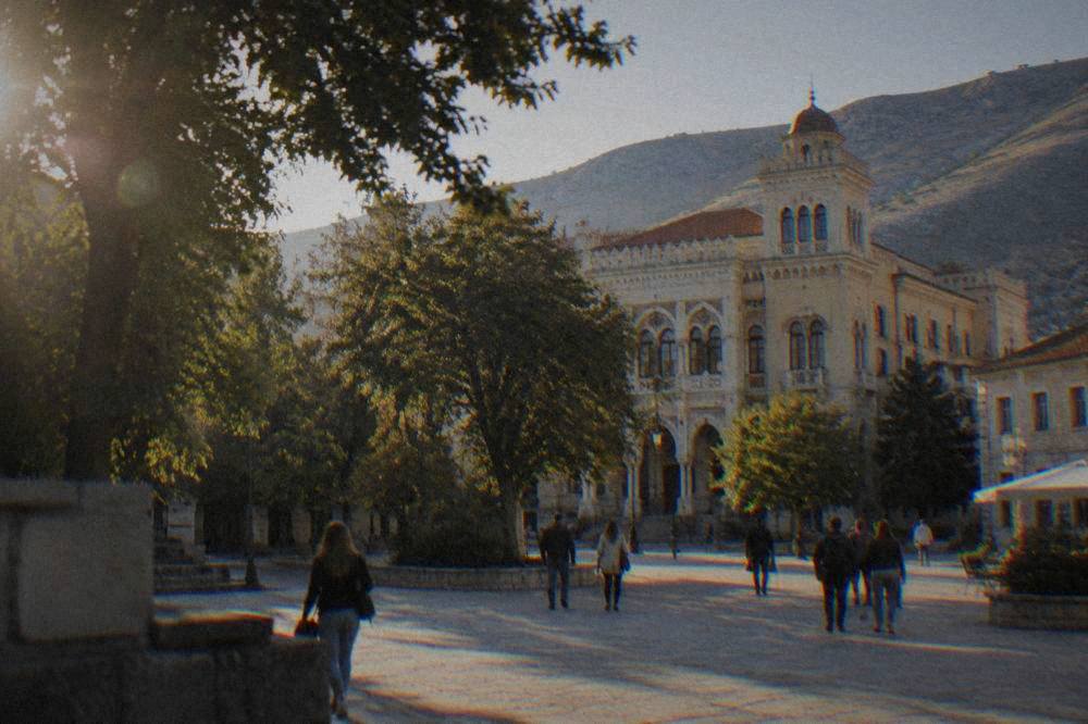 Spanish Square in Mostar with the Gymnasium building and people crossing the plaza