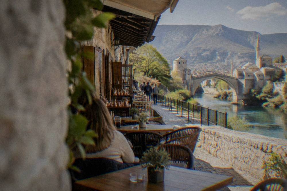 A cafe terrace on a west Mostar street with tables and chairs in afternoon light