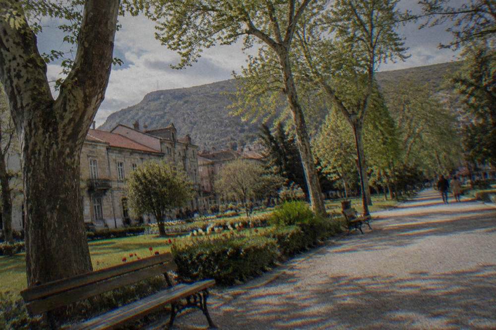 A pedestrian street in central Mostar with park trees and period buildings near Zrinjevac