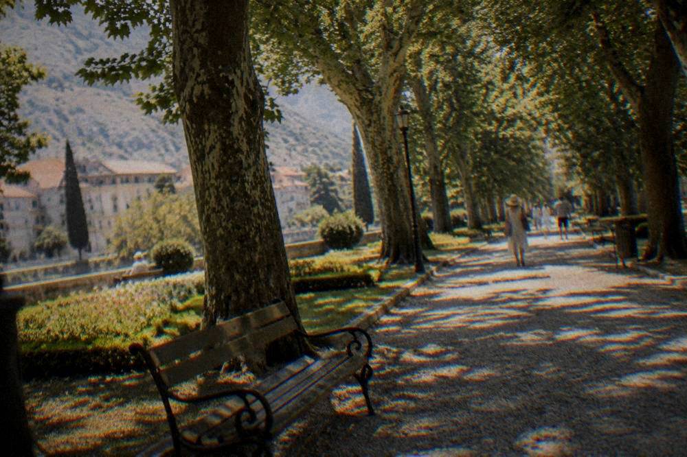 Shaded path and benches in Zrinjevac park in Mostar on a summer morning