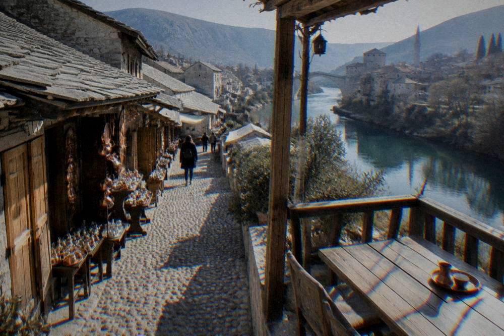 A wooden terrace of an old stone house overlooking a small river in Mostar
