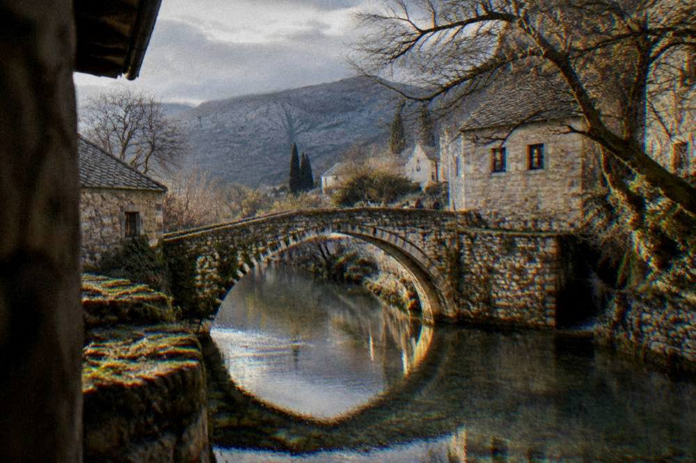 A quiet stone bridge over a small river with reflections in the water at dusk