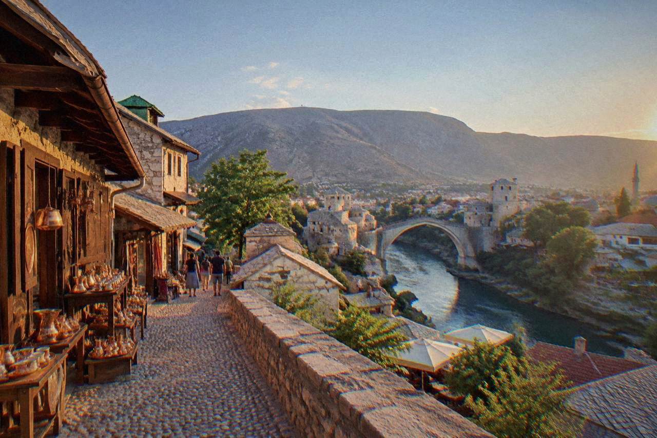 View from a hillside platform over the rooftops and bridges of Mostar along the Neretva river