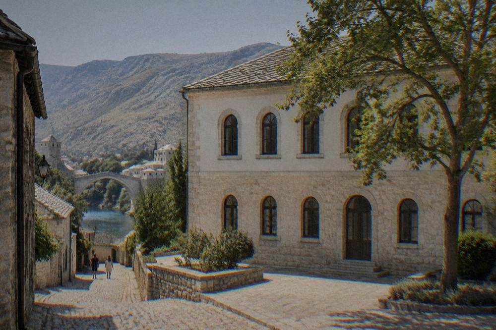 Cobblestone lane with stone buildings leading toward the Neretva river