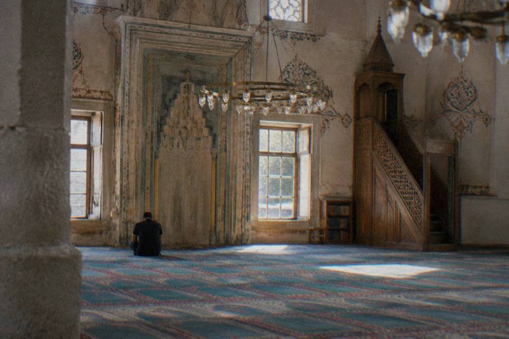 Interior of an Ottoman mosque with patterned carpet, painted walls and hanging lamps