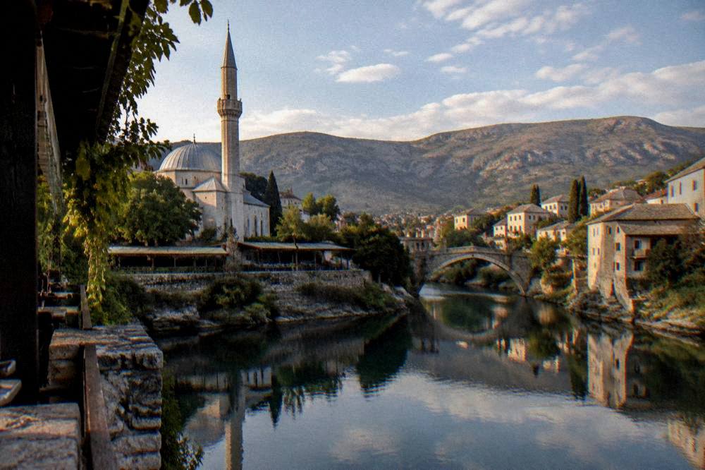 Evening view over a small stone bridge and calm river with old houses reflected in the water