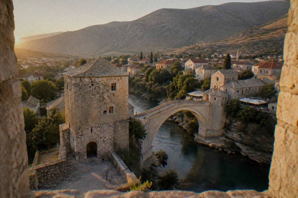 A view over a pale stone bridge and rooftops from a tower window