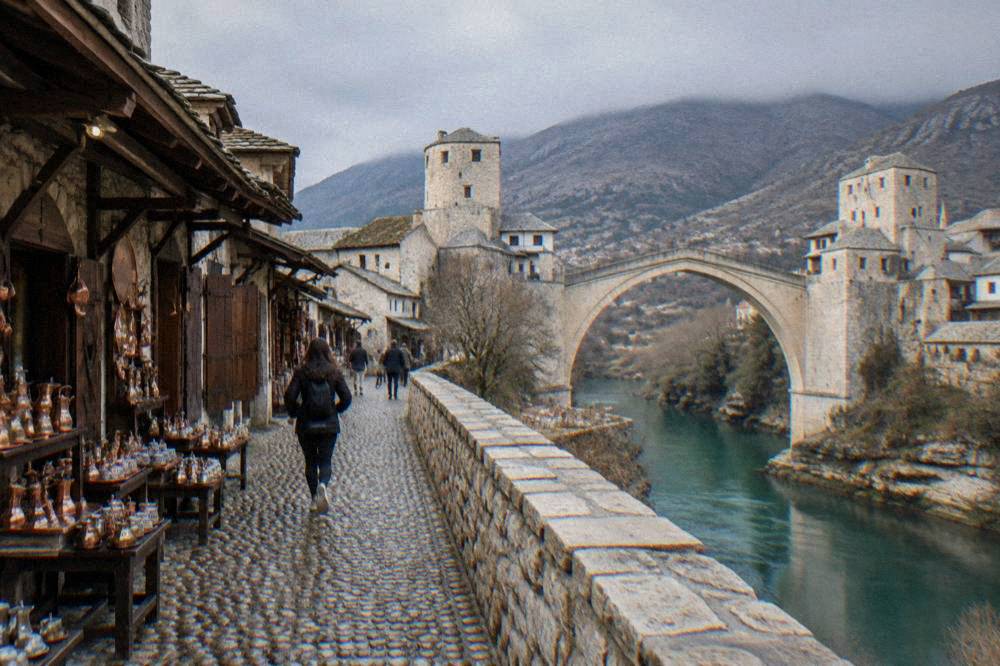 Narrow cobbled street in Mostar's Old Town with stone walls leading toward the Old Bridge