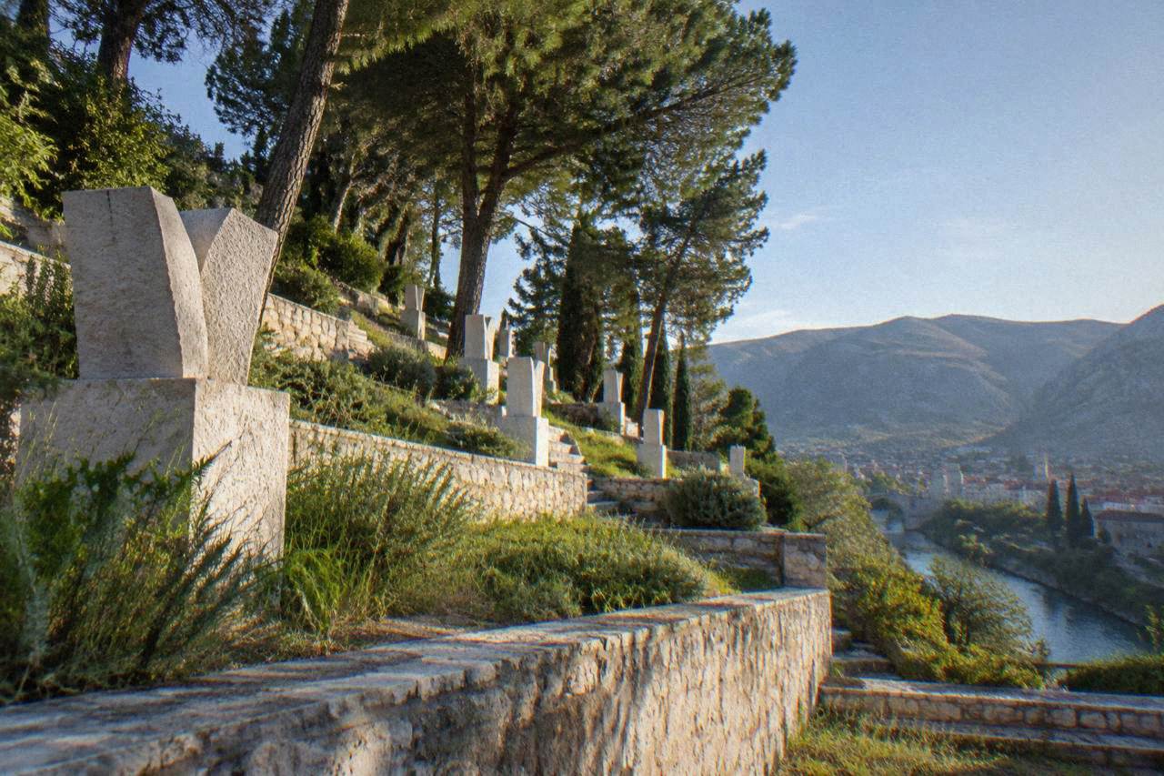 Stone terraces of a hillside memorial cemetery with carved markers under trees