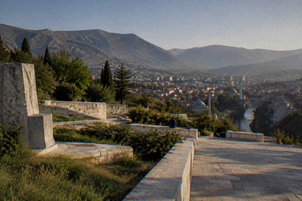 A ceremonial stone plateau overlooking a city skyline with minarets and hills
