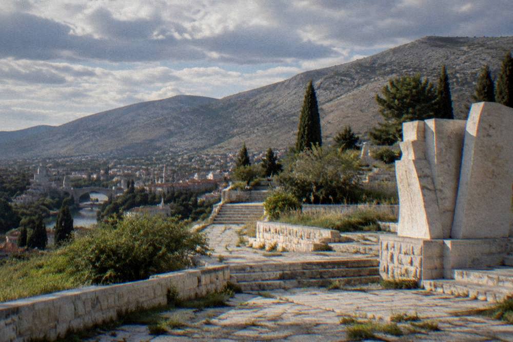 Morning light falling across empty stone terraces with wild plants between paving