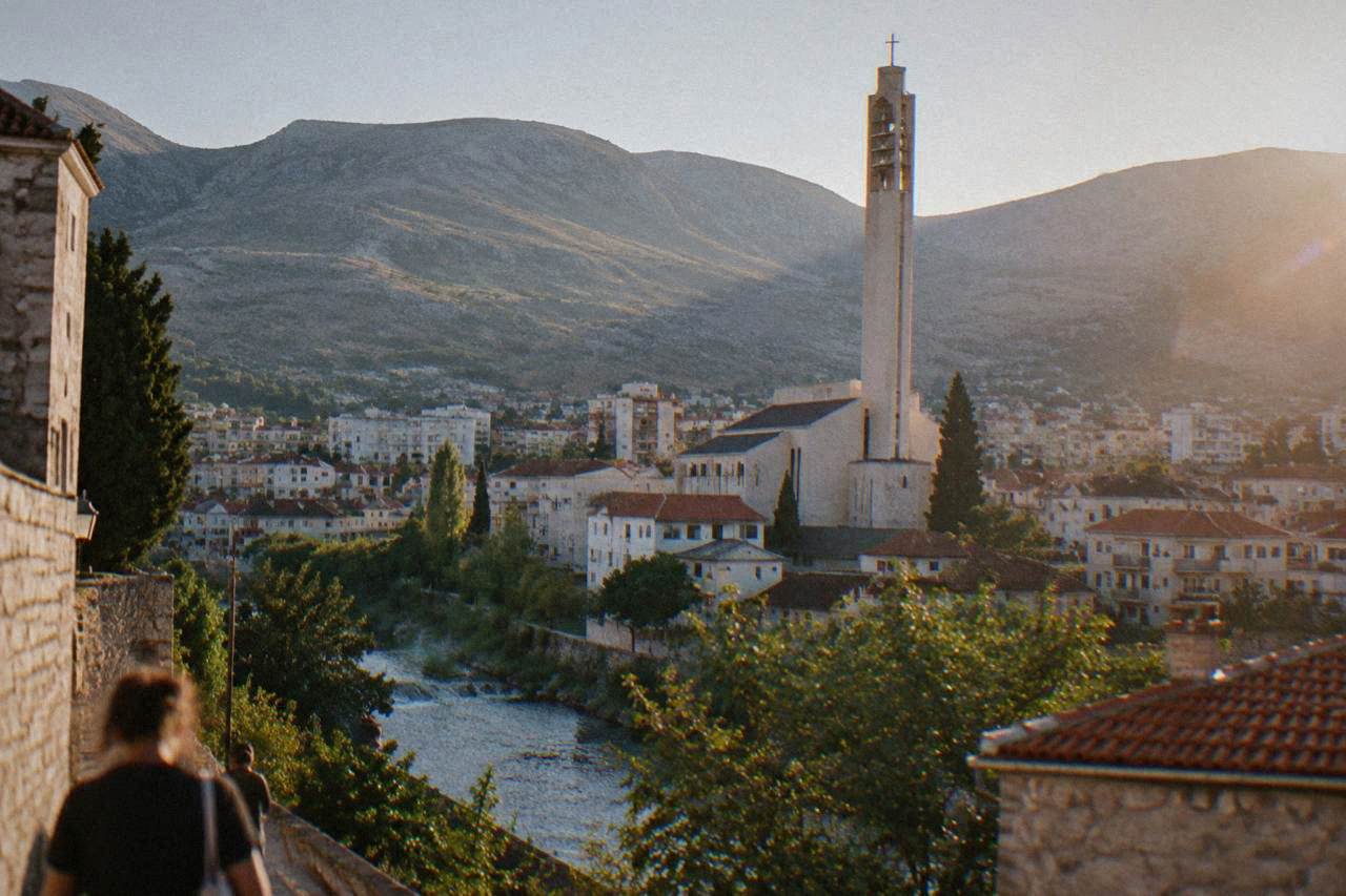 The tall bell tower of the Franciscan Church of Saints Peter and Paul rising above rooftops in Mostar