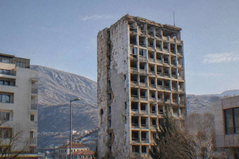 Looking up at the empty window grid of a war-damaged concrete tower against the sky