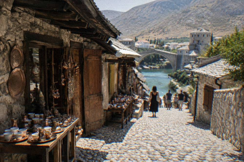 A narrow stone-paved street in the old town of Mostar leading down toward the river
