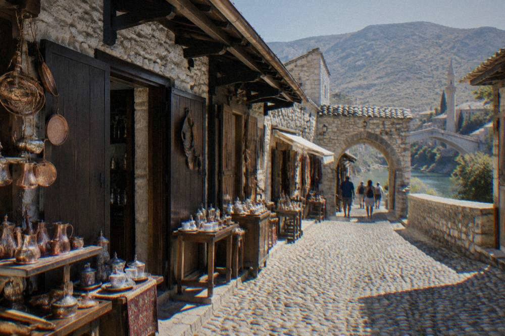 A narrow stone lane in Mostar Old Town with an arched doorway and hanging sign