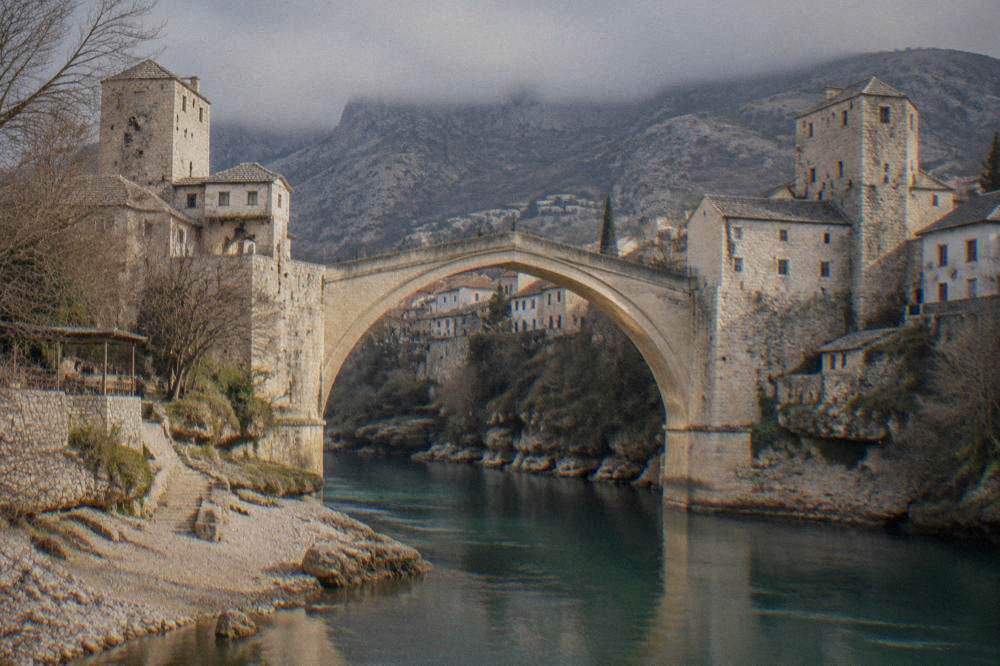 The stone arch of the Old Bridge in Mostar seen from the riverbank