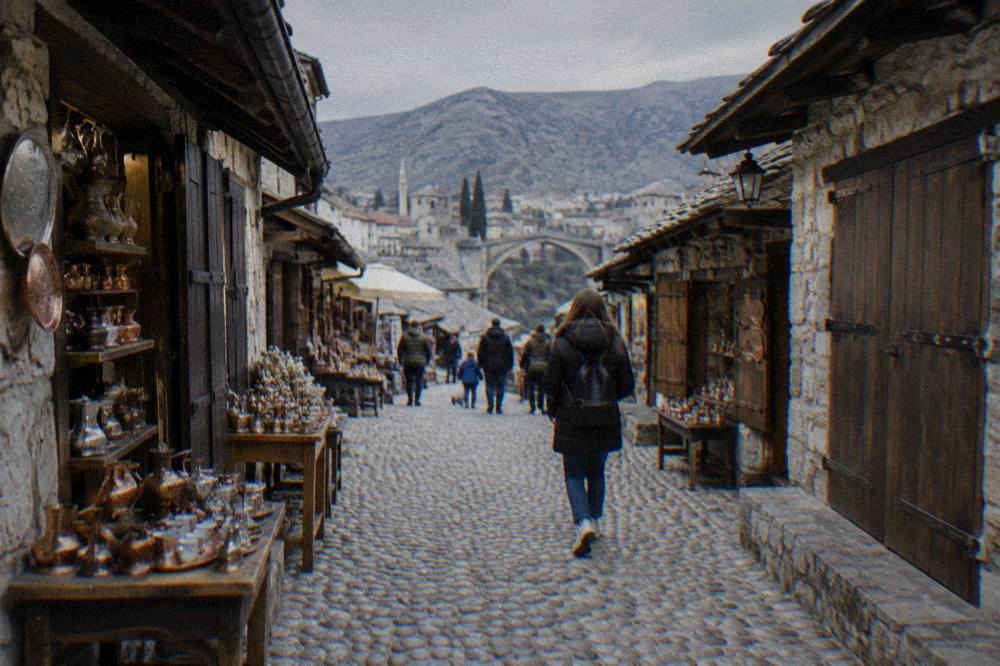 Families and visitors walking the pedestrian bazaar street beside the Neretva in Mostar