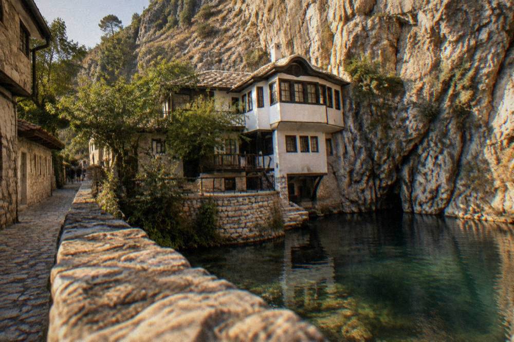A narrow village street with stone houses and a cliff wall rising behind them