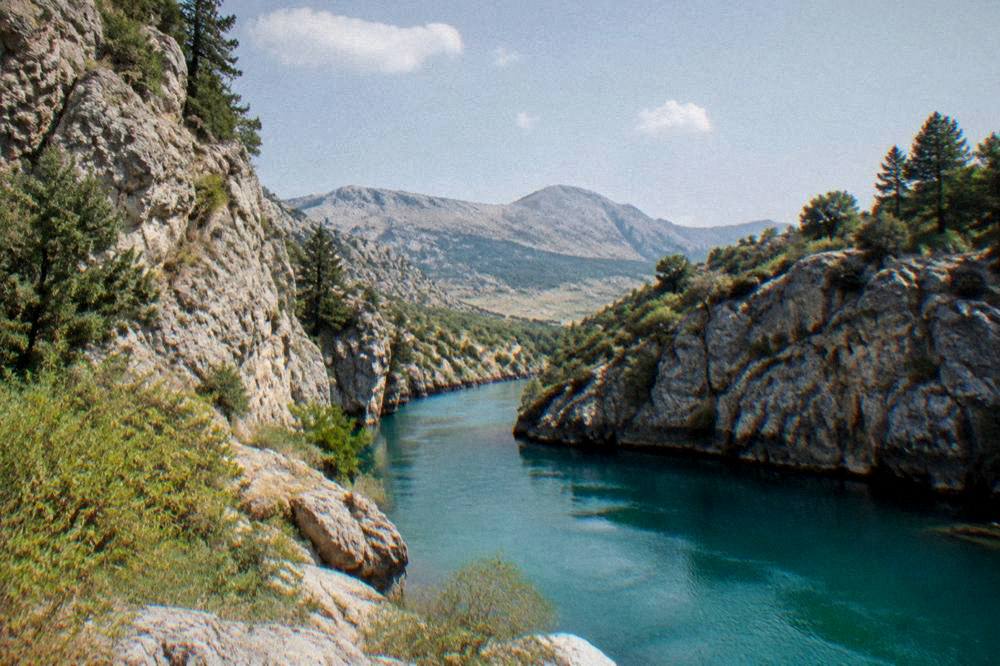 A turquoise mountain river flowing between steep rocky canyon walls