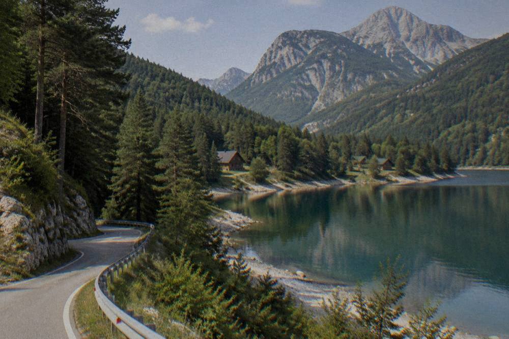 A winding road through pine forest climbing toward a mountain lake
