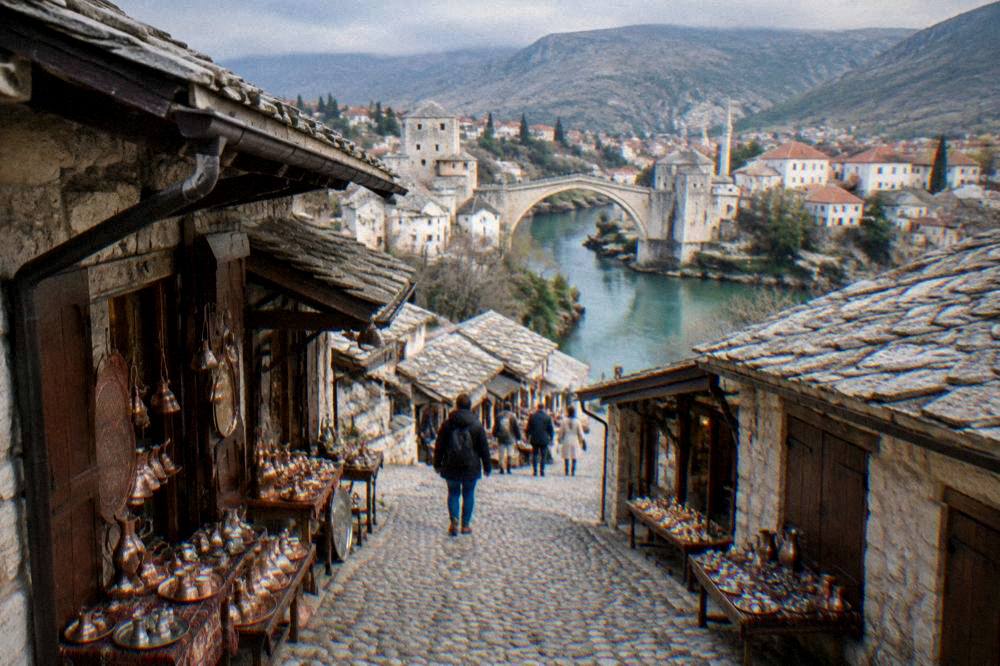 A red-tiled old town skyline with a river bridge and green hills behind