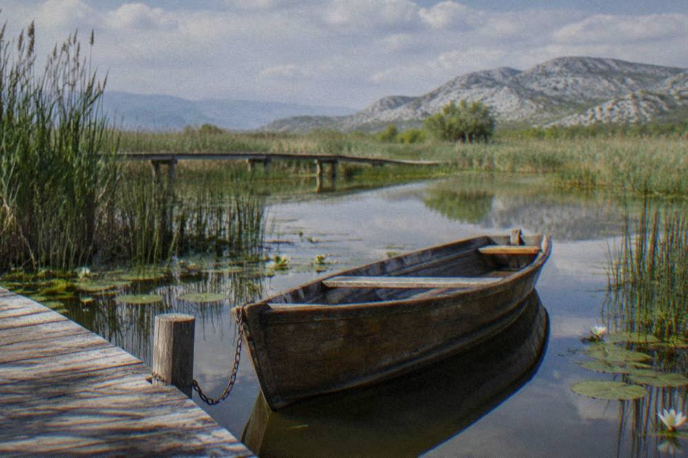 A wooden boat moored at a jetty on a calm lake surrounded by reeds