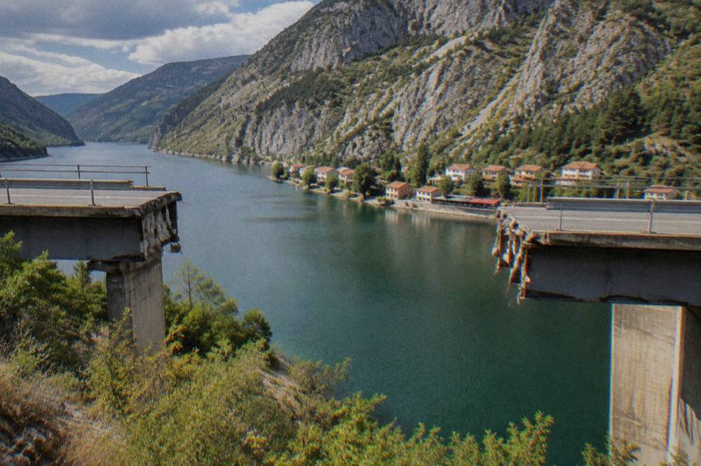 Closer view of the severed steel span of the broken bridge with the canyon wall behind