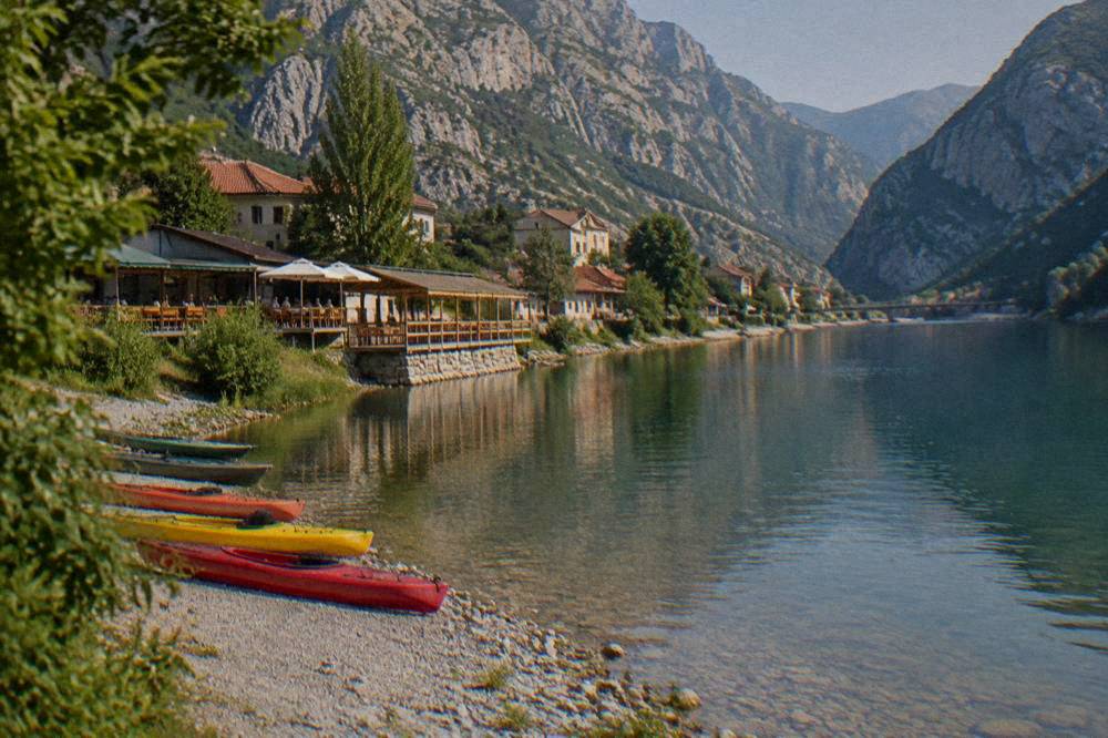 Kayaks resting on a pebble bank beside the green Neretva river