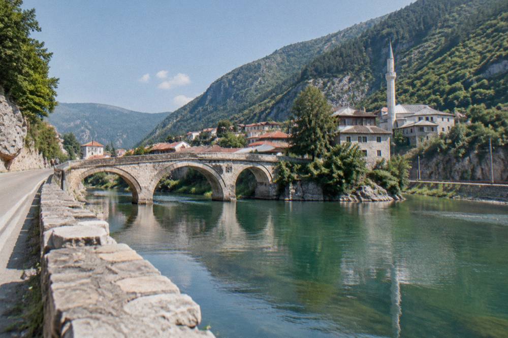 Winding road along a steep river canyon with a rail line visible across the water