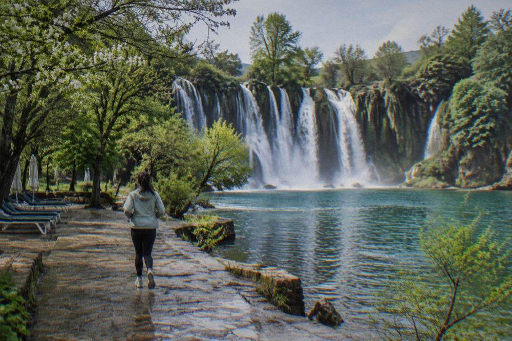 Trees turning green around the waterfall pool in late spring with empty sunbeds