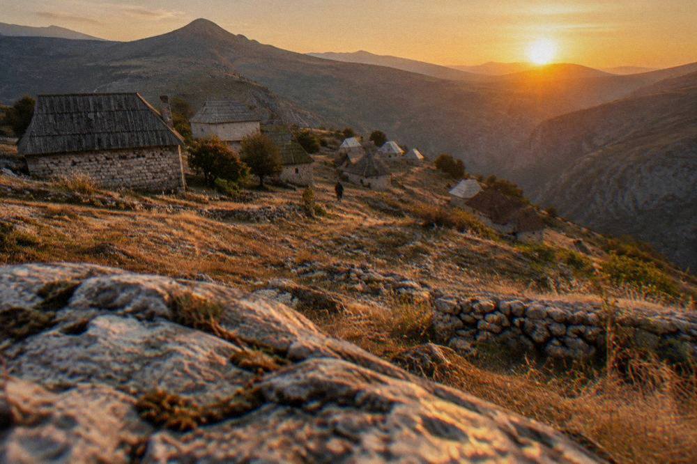 Sunset light over ridgelines above a highland village with stone rooftops