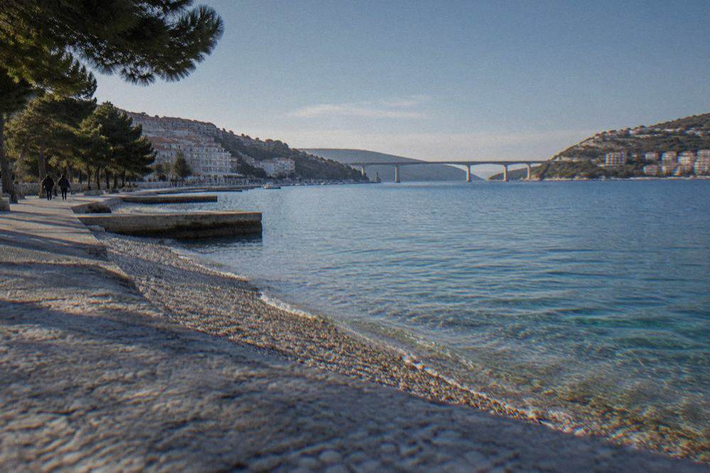 A long bridge on stone piers crossing a strait between the mainland and a peninsula at dusk