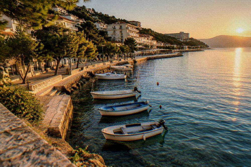 Fishing boats moored in clear shallow water beside a stone quay in late golden light
