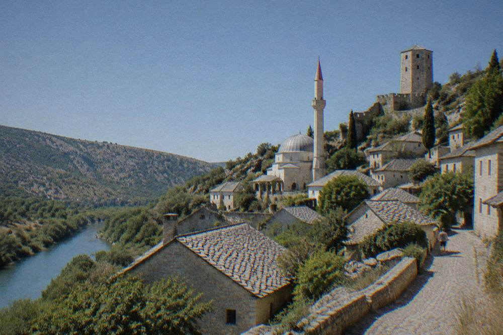 The domed mosque of Počitelj with its minaret against a clear sky above the village rooftops