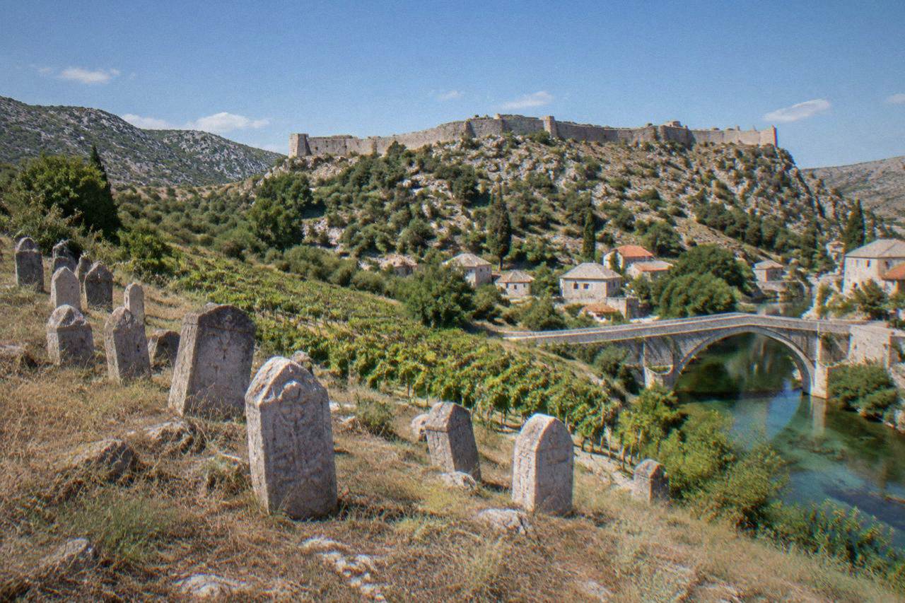 Rows of carved medieval stone tombstones on a hillside above vineyards near Stolac