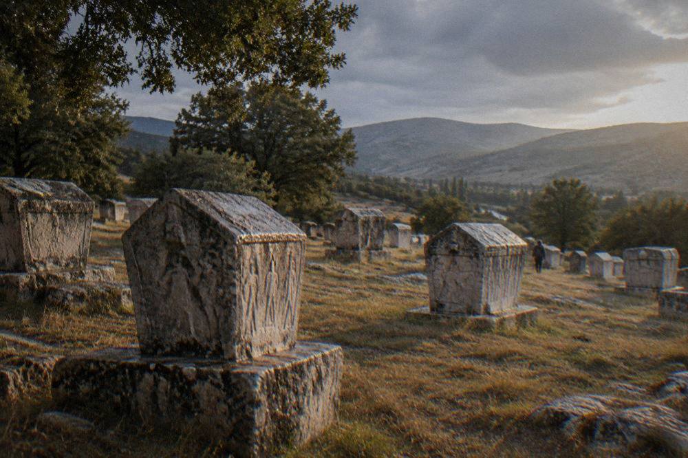 Low evening light raking across rows of carved tombstones at the necropolis