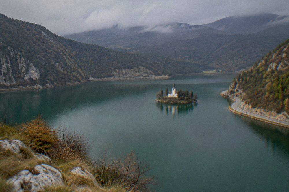 A mountain lake surrounded by green hills with a quiet shore road