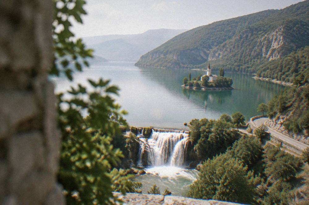 A wide waterfall curving into a pool ringed by trees and low cliffs