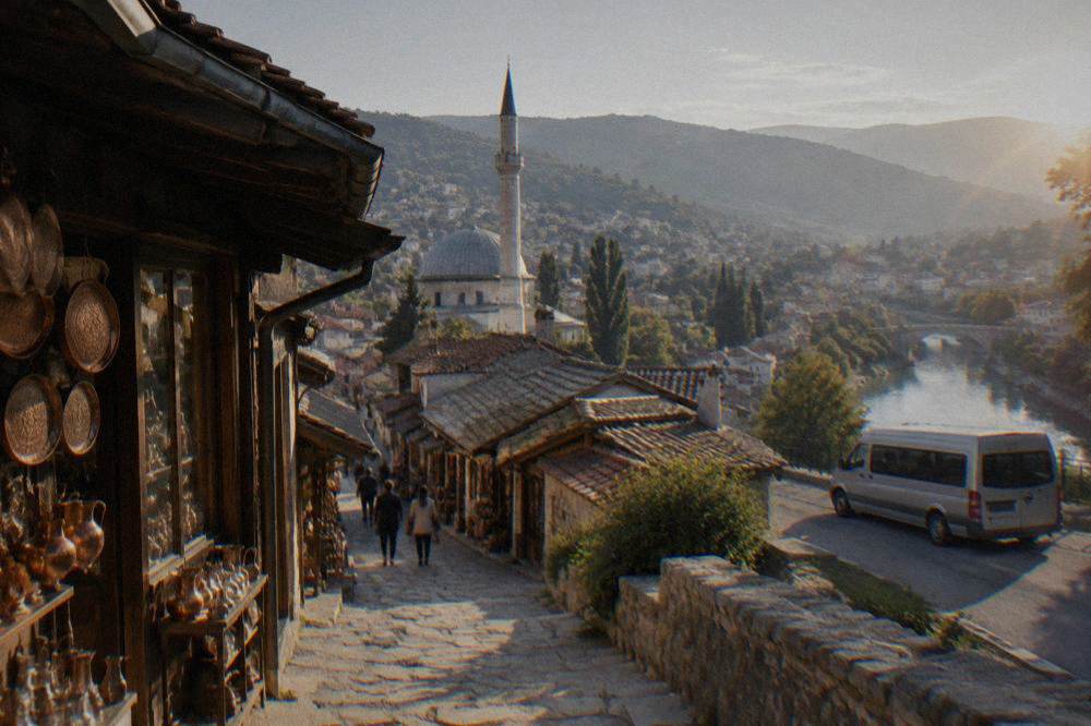 A small tour van parked on a roadside viewpoint above a river town in Herzegovina
